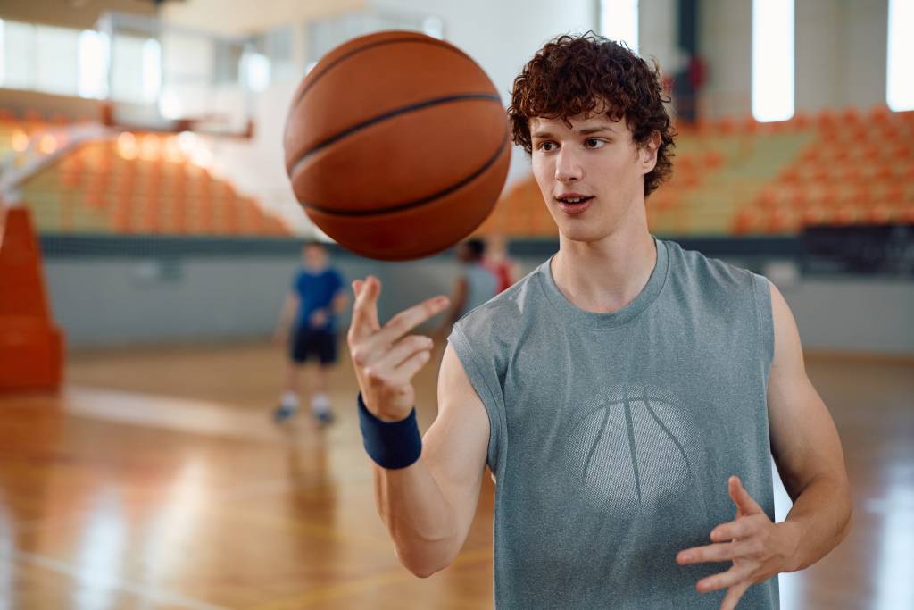 A college athlete spinning a basketball on his finger.