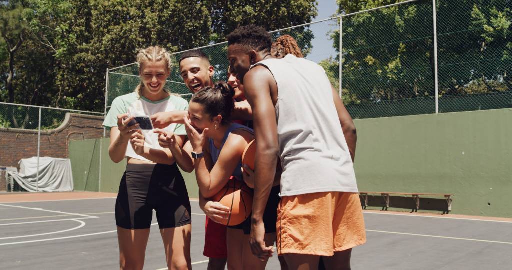 A group of six college athletes, men and women, on an outdoor basketball court.