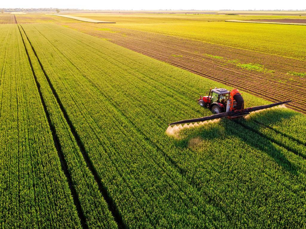 An aerial shot of a tractor spraying crops.