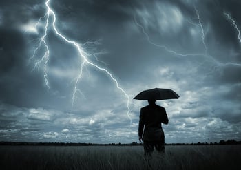 Businessman with umbrella caught in storm