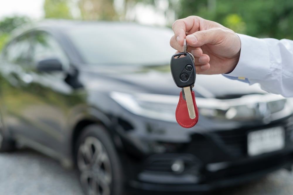 person holding car keys in front of a car