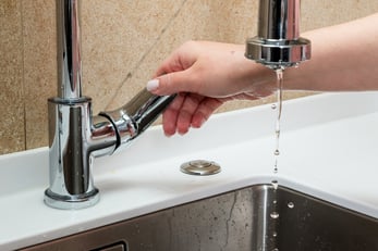 Hand turning on a faucet