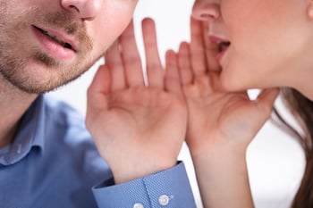 woman whispering in a man's ear