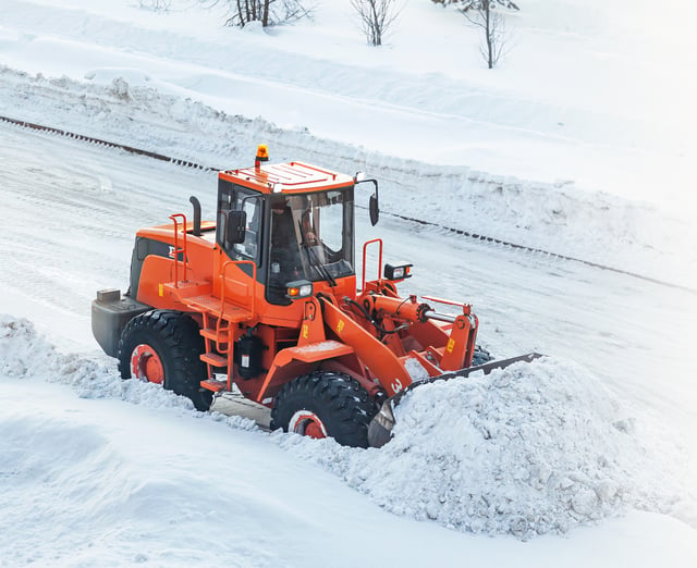 Orange tractor plows snow