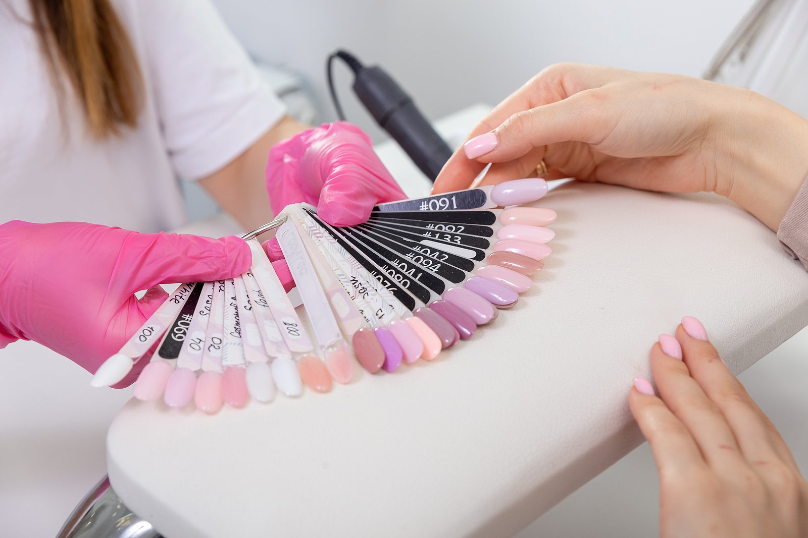 Nail technician displays nail polish color options to a client