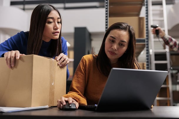 coworkers looking at a laptop in a warehouse