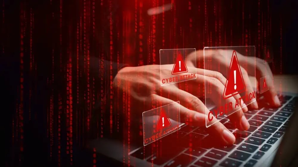 Fingers typing on a keyboard with visualizations of cyber attacks.