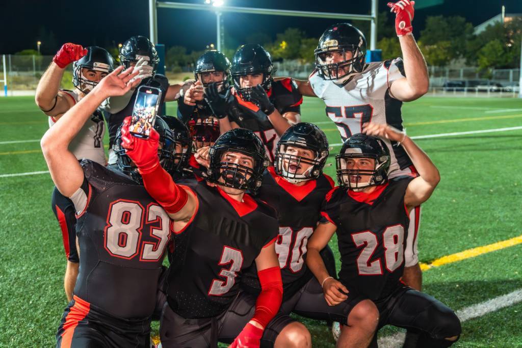 Football players cheering and taking a selfie as a group.