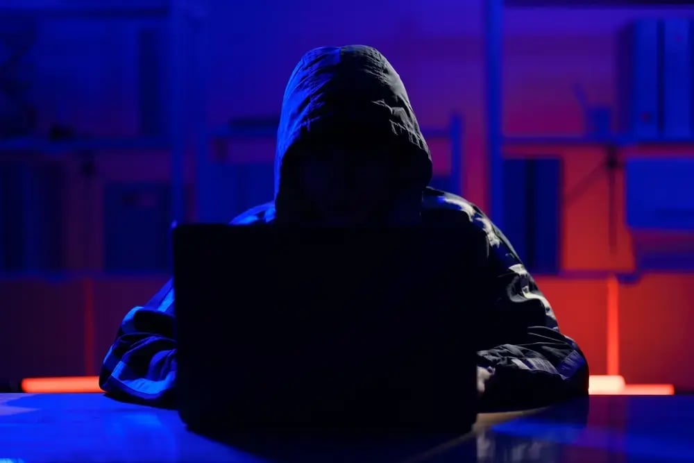 A hacker wearing a hoodie in the dark.