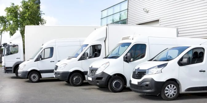 Fleet of white commercial vehicles in parking lot