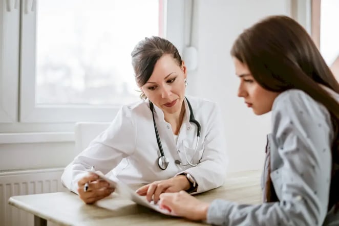 Female doctor looks at medical records with female patient