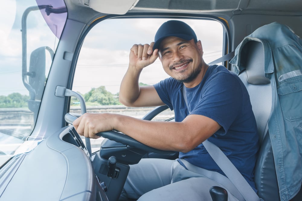 man sitting in commercial truck tipping his hat and smiling