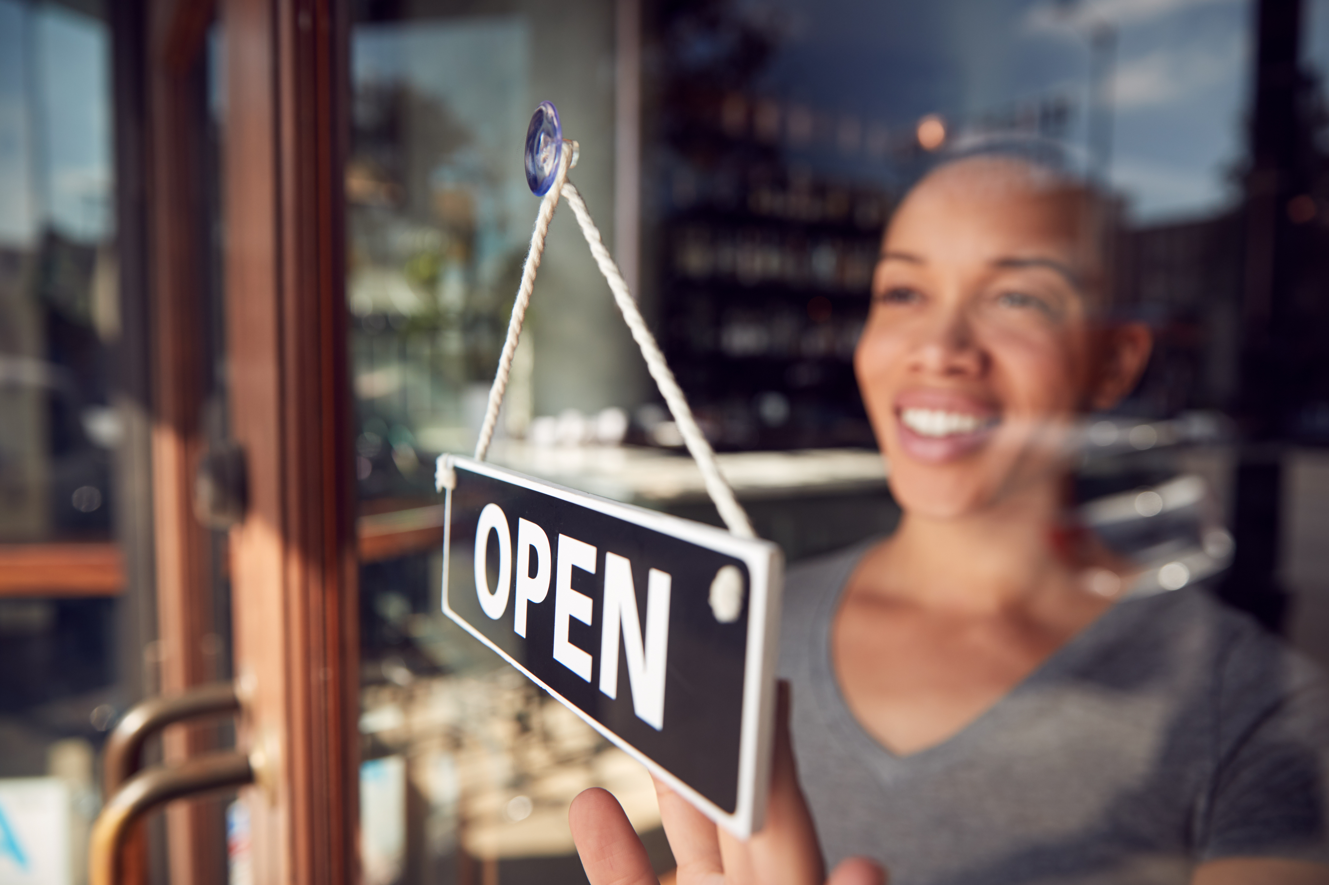 Women looking out the window in front off an open sign