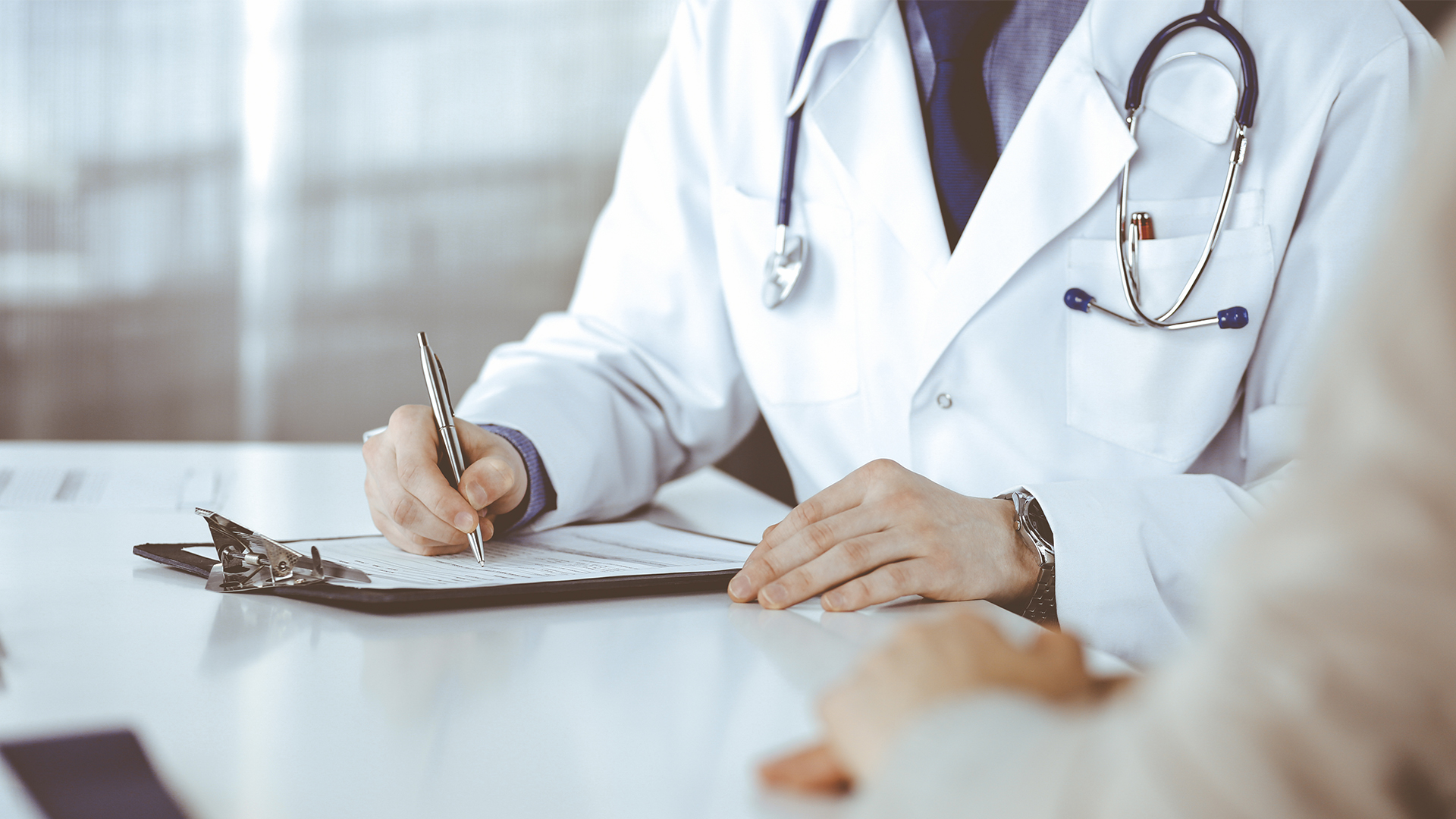 Doctor writing on clipboard